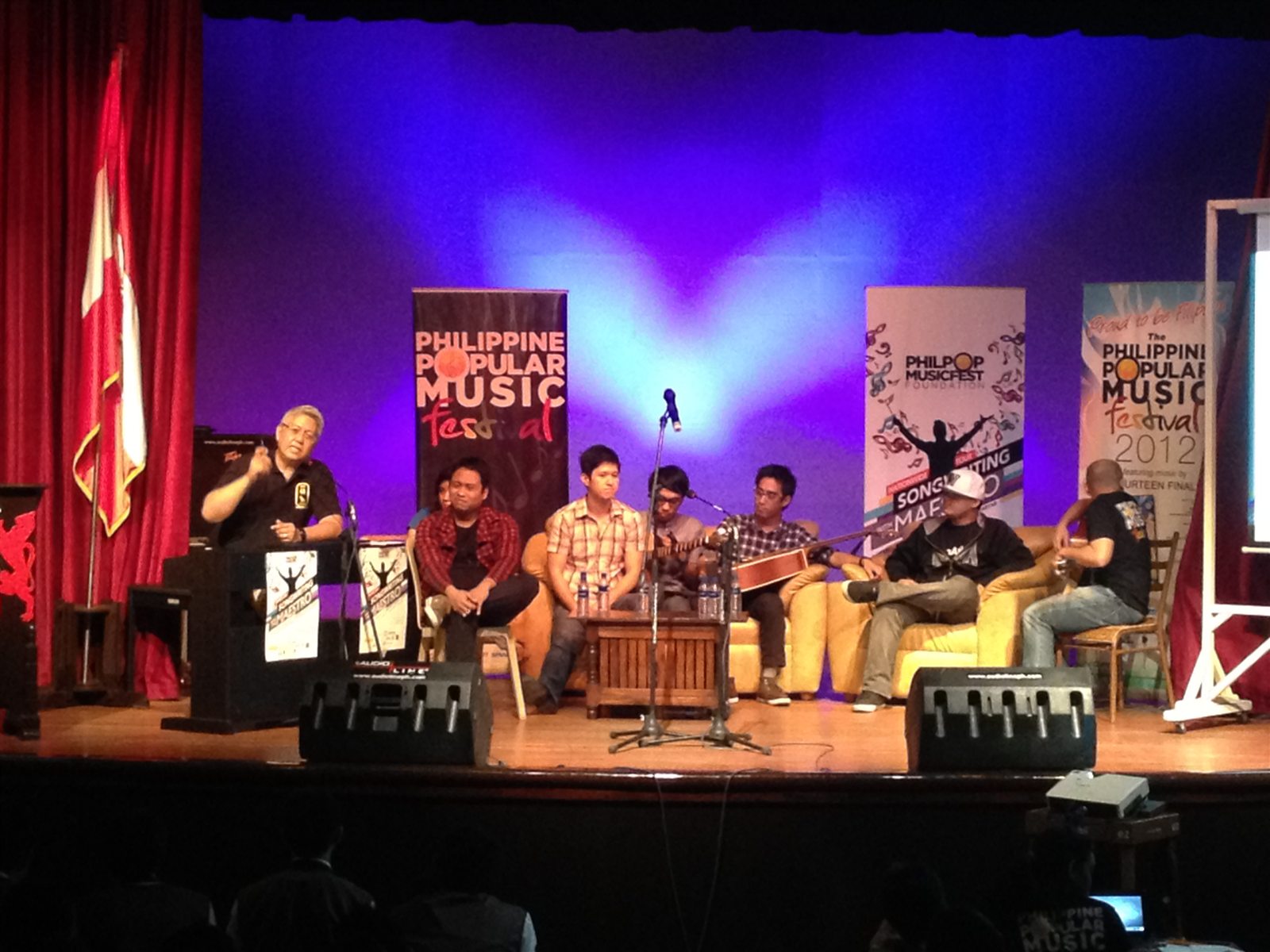 Music program with speakers, microphones, musicians, and a purple stage wash